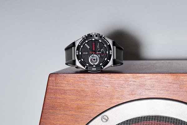 A Hugo Wild black leather strap men's watch on a wooden table.