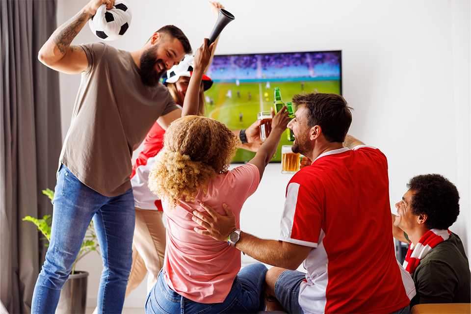 A family watching a live match on TV connected to TP-Link Wi-Fi and cheering for the winning team.