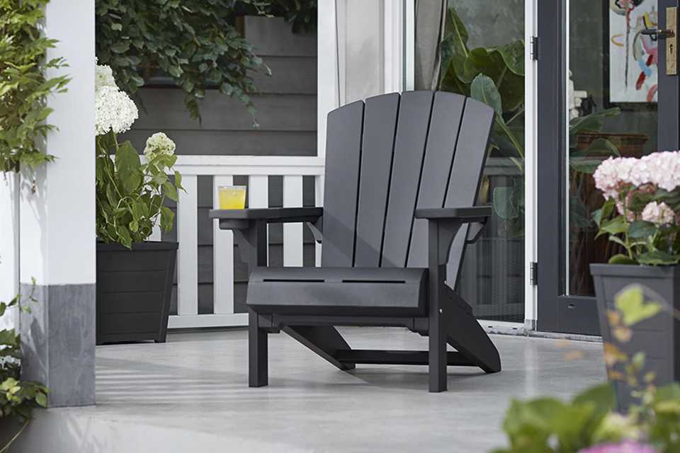 Keter Plastic Adirondack garden chair on patio with flowerpots placed on either side.