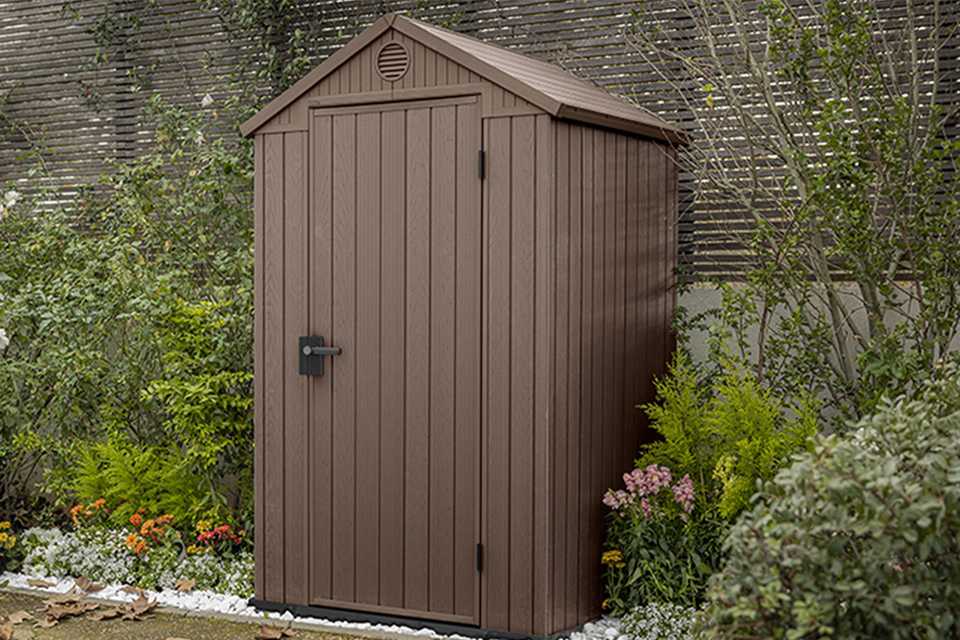 Keter Darwin Apex brown garden storage shed surrounded by plants.