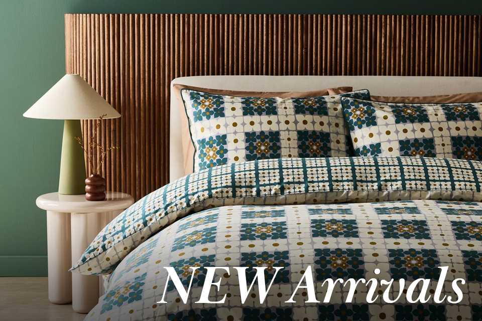 Printed blue floral bedding with green lamp on marble side table.