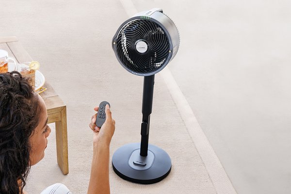 woman remotely controlling a pedestal fan