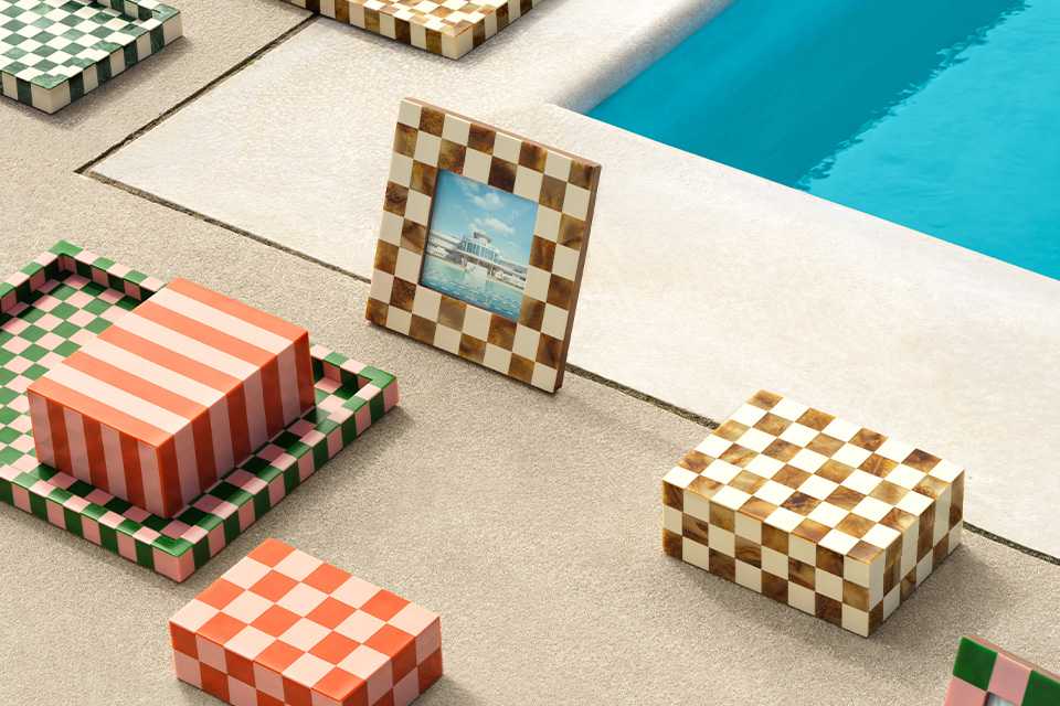 Habitat picture frames and trinket trays with colourful check patterns placed next to a pool.