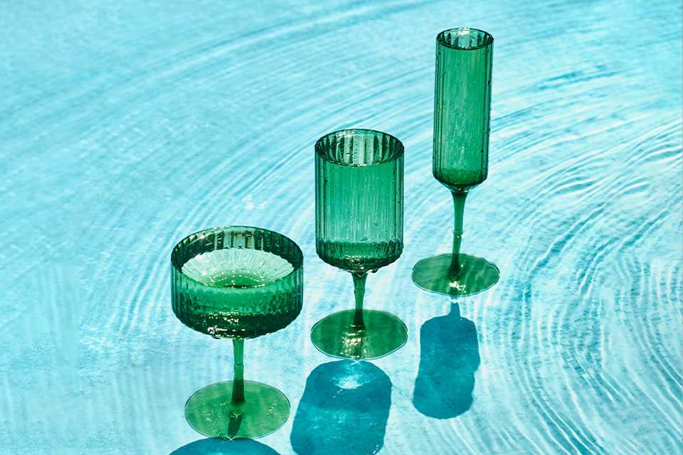 Habitat green glassware placed in a clear blue pool of water.