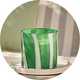 A large white and green Habitat large citronella multiwick candle with a striped effect on an outdoor patio set.