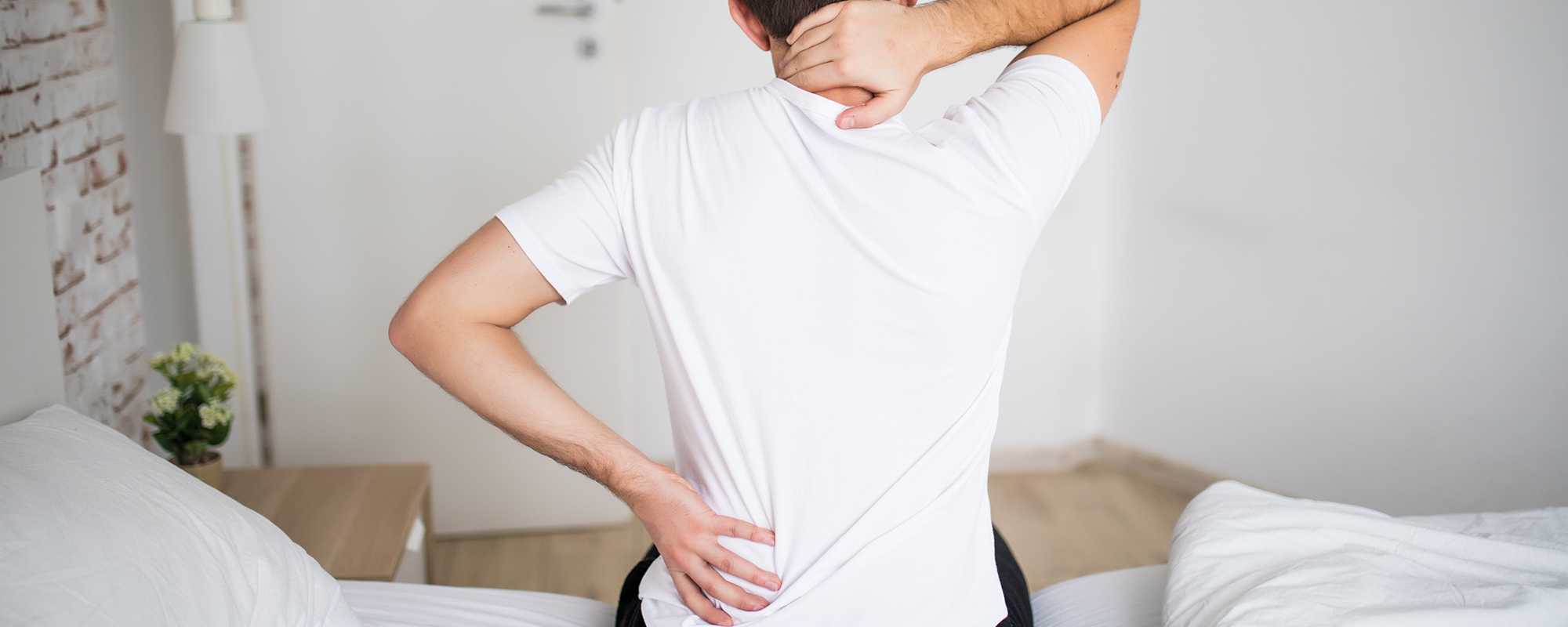 Man suffering from back pain at home in the bedroom.