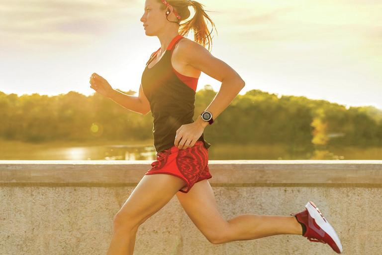 Woman running outside in cold weather with a long sleeve top, leggings and running gloves on.