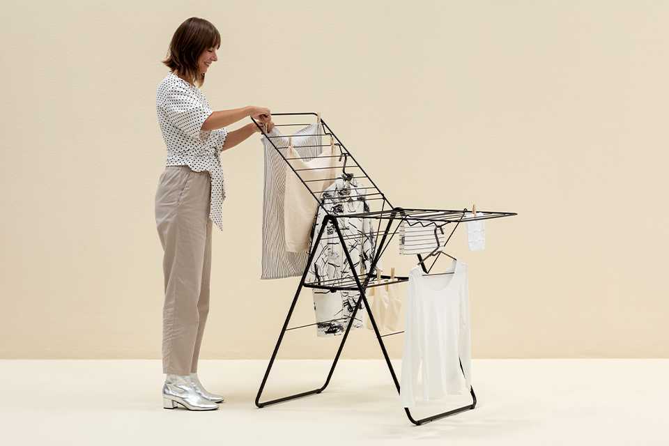 A woman hanging clothes on a Brabantia drying rack.