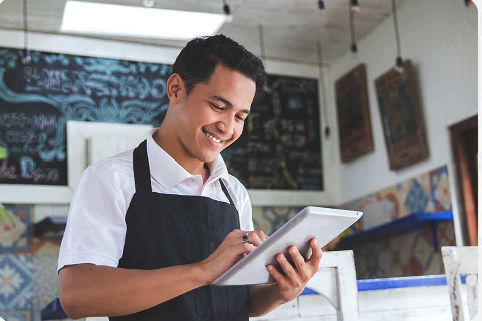 A man smiling while looking at a tablet.