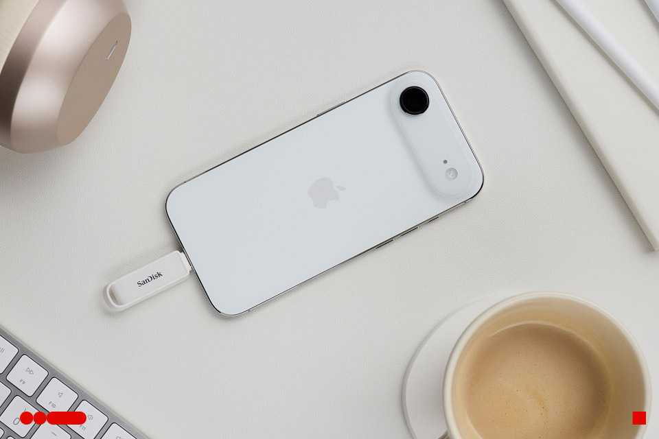SANDISK phone drive with USB-C plugged into an iPhone placed on a desktop.