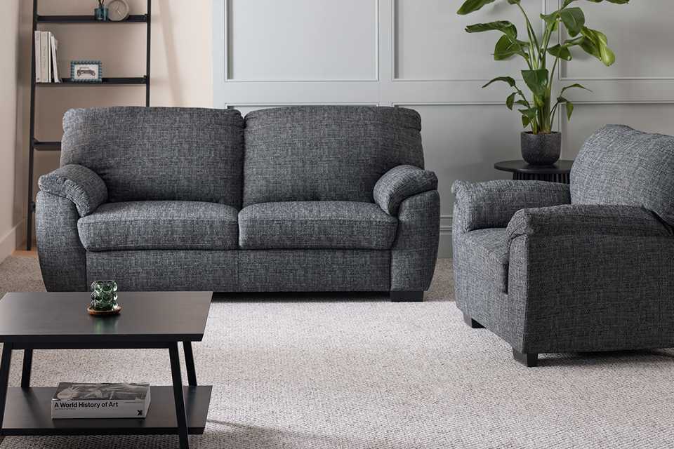 A charcoal Argos Home Milano Fabric chair and 3 seater sofa set in a living room next to a ladder shelf and a coffee table.