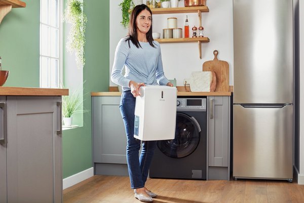 A woman carrying a Dimplex 14 Litre Dehumidifier.