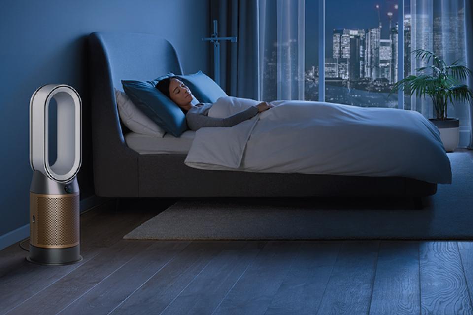 Woman asleep in bed, with a dyson air purifier in the room.