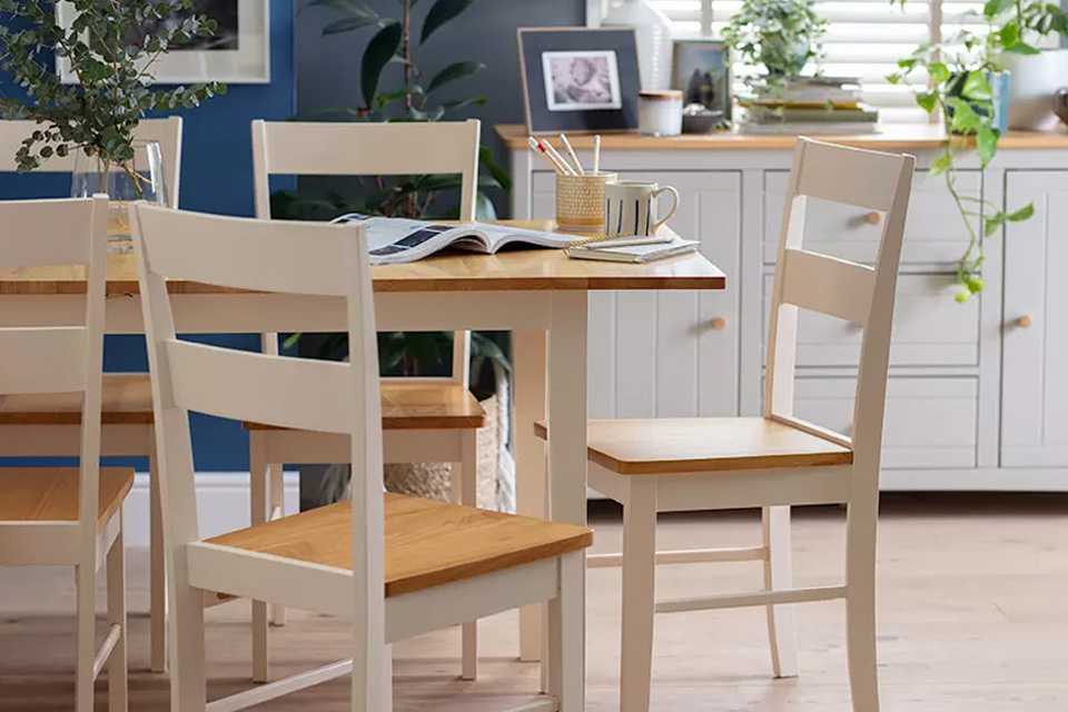 A white and natural wood rectangular dining set in a navy blue room.