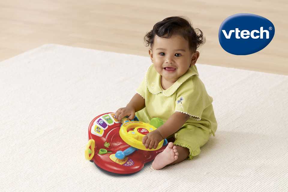 A child playing with a Vtech TinyTot Driver toy.
