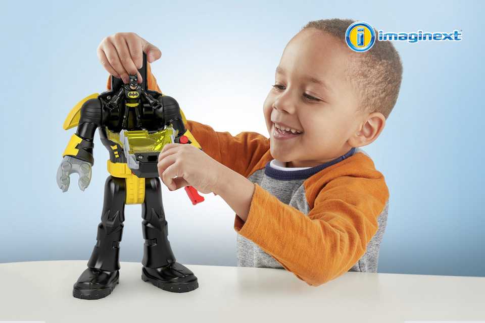 A young boy playing with an Imaginext DC Super Friends Batman Insider & Exosuit playset.