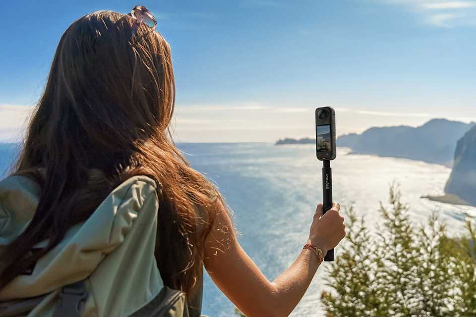 A woman using an Insta360 X4 action camera to shoot a travel video.