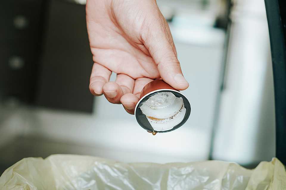 A person disposing a coffee pod after using it.