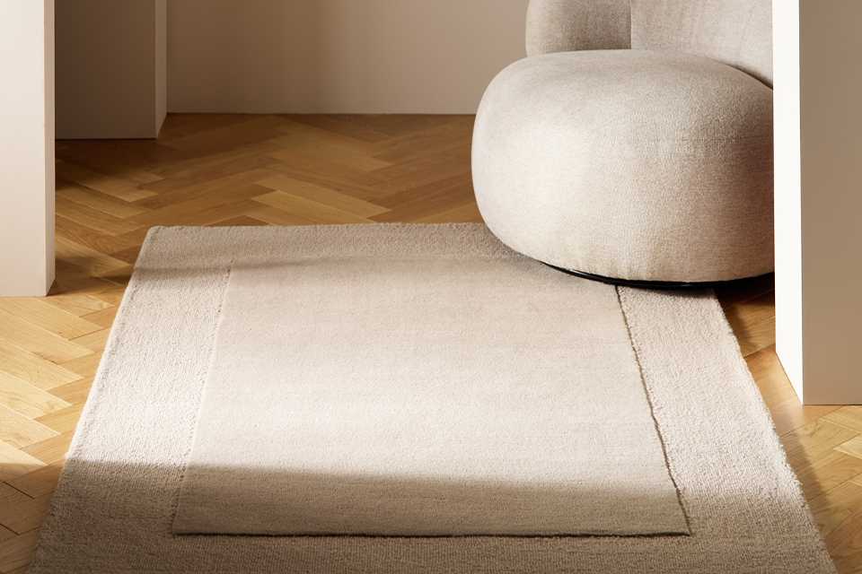 Habitat Simple Border Taupe Wool Cut Pile rug with an arm chair placed in a living room.