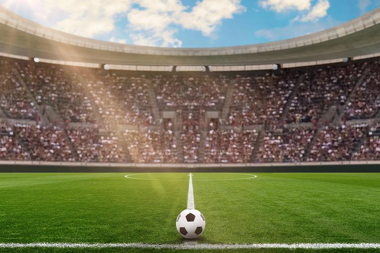 Black and whote football on the centre line of a football pitch.