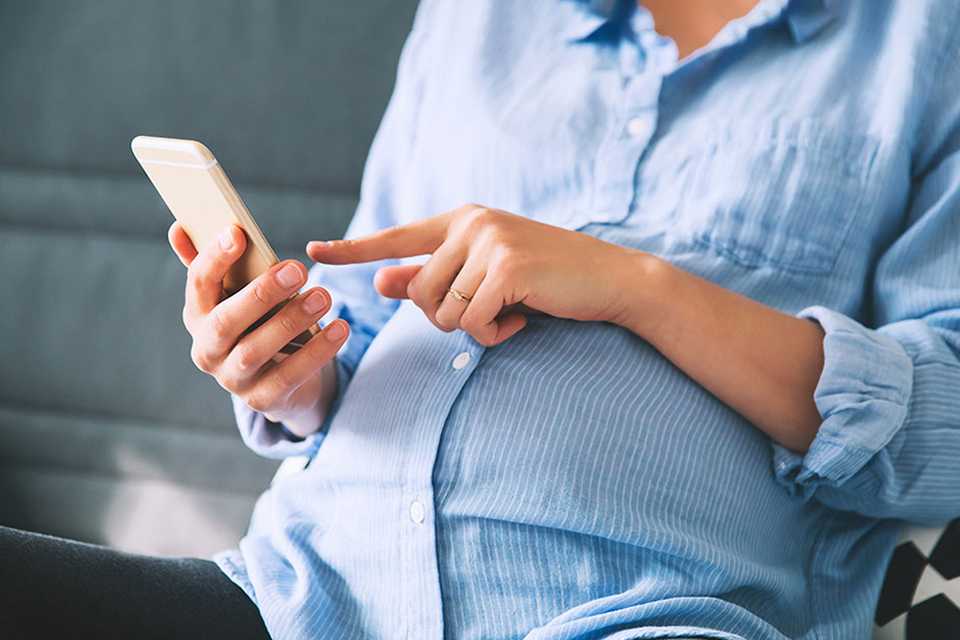 A pregnant lady scrolling through her phone.