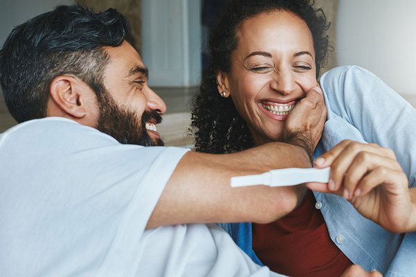 A happy couple looking at a pregnancy test stick.