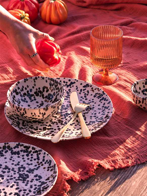 Habitat Jackson dinnerware set placed on a table outdoors with a red tablecloth on it.