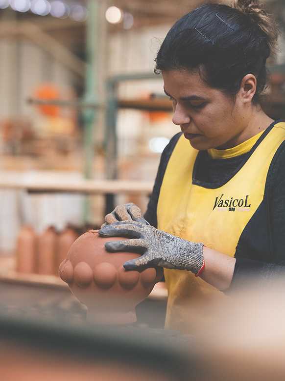 A woman working on a Habitat terracotta vase in a factory.