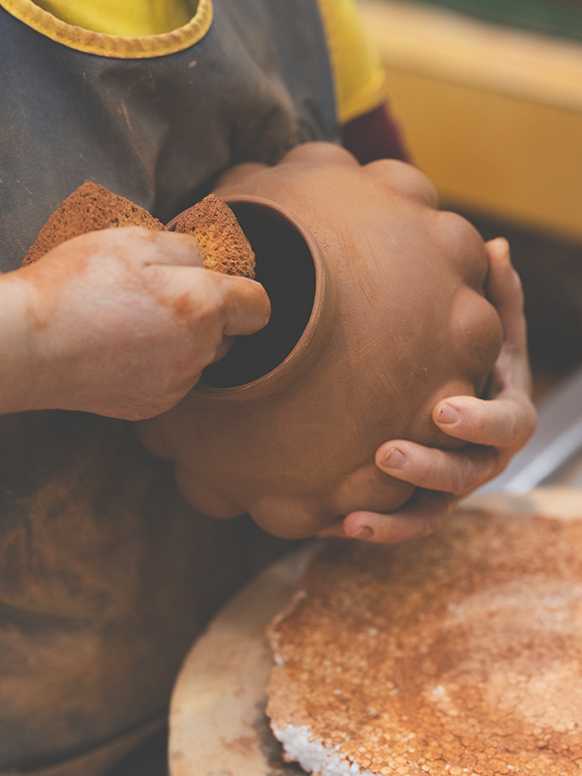 A person working on a Habitat terracotta vase in a factory.