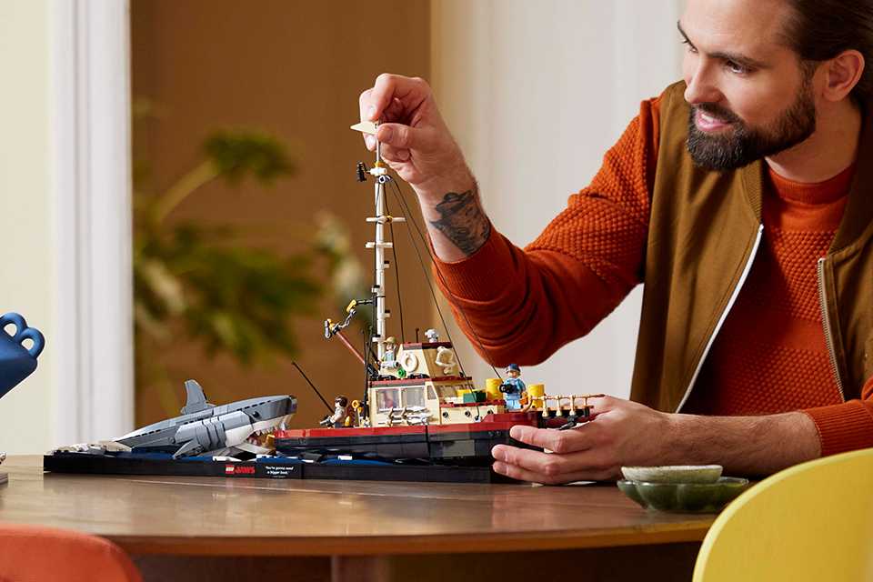 Man modelling the LEGO® Jaws set with shark and boat.