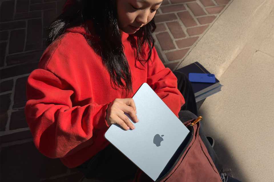 A girl placing an Apple MacBook Air 2025 into her bag.