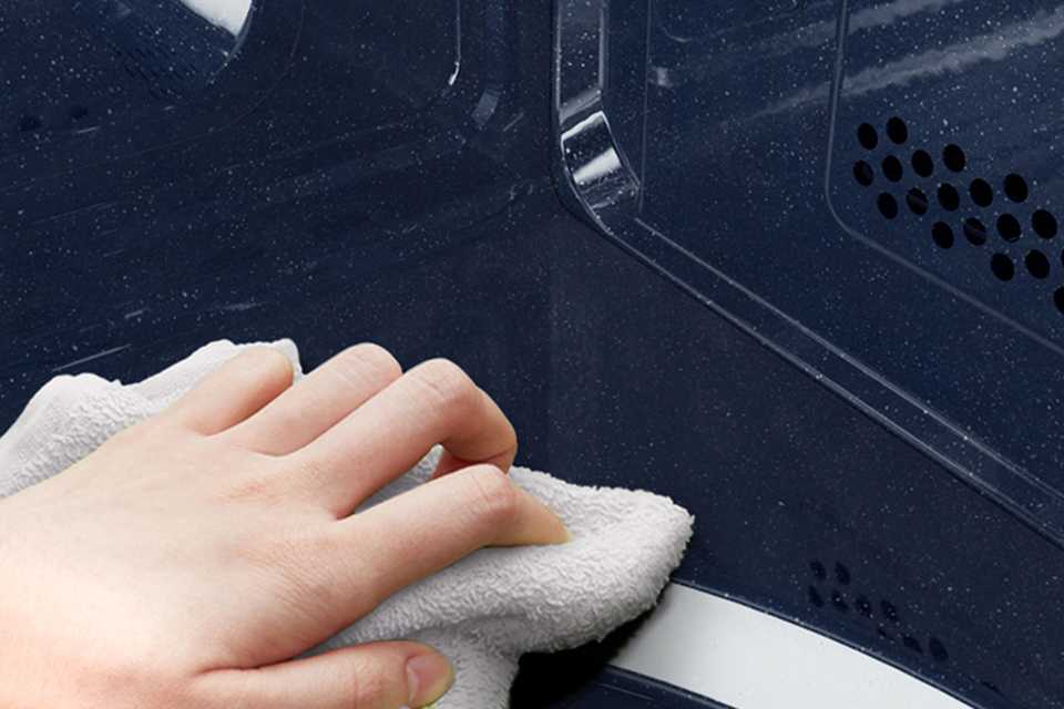 A person cleaning a microwave with a cloth.