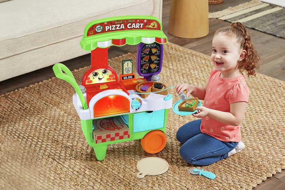 A girl playing with a LeapFrog Build-A-Slice Pizza Cart.