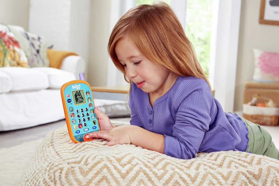 A girl playing with a Vtech Bluey Ring Ring phone.