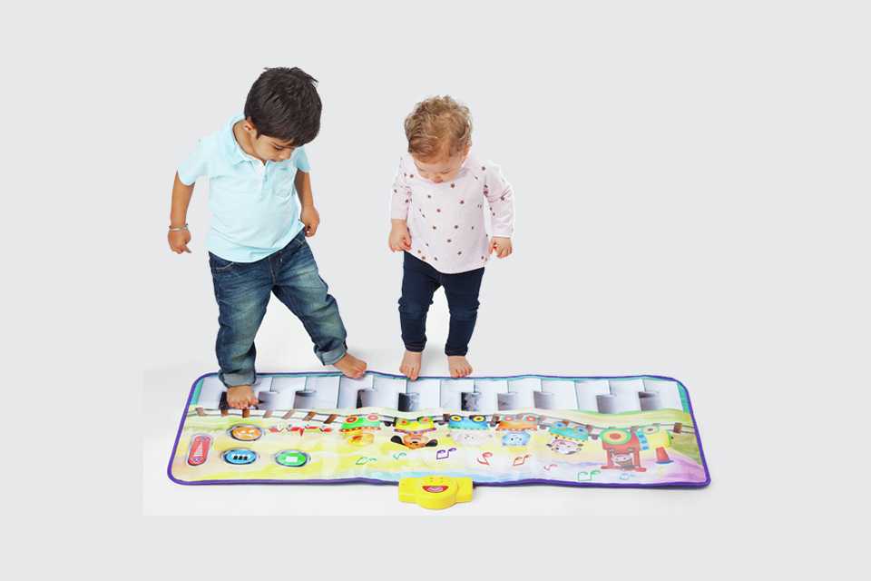 Two kids playing with a Chad Valley giant floor piano.