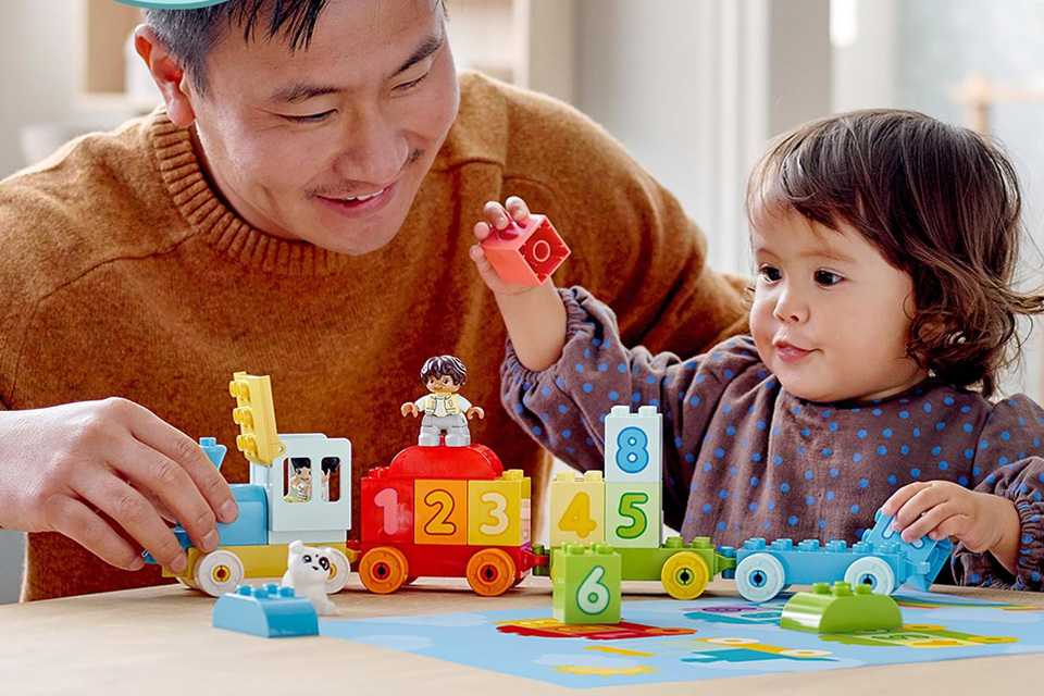 A little girl and her father playing with a LEGO DUPLO My First Number Train toy for Toddlers.