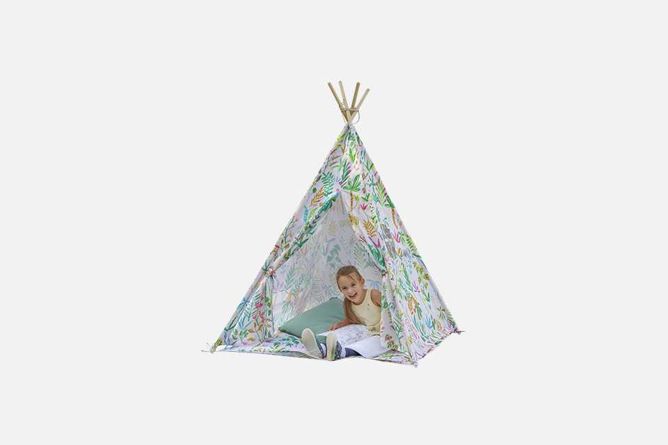 A small girl in a forest printed teepee play tent.