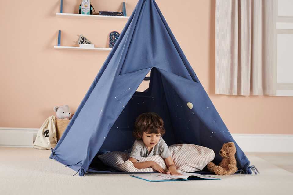 A kid inside a Great Little Trading Company Play Space Teepee in blue.