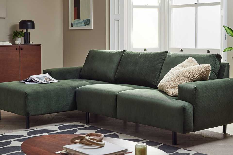 - A Habitat Julien Fabric Left Hand Corner Chaise green Sofa near a walnut sideboard.