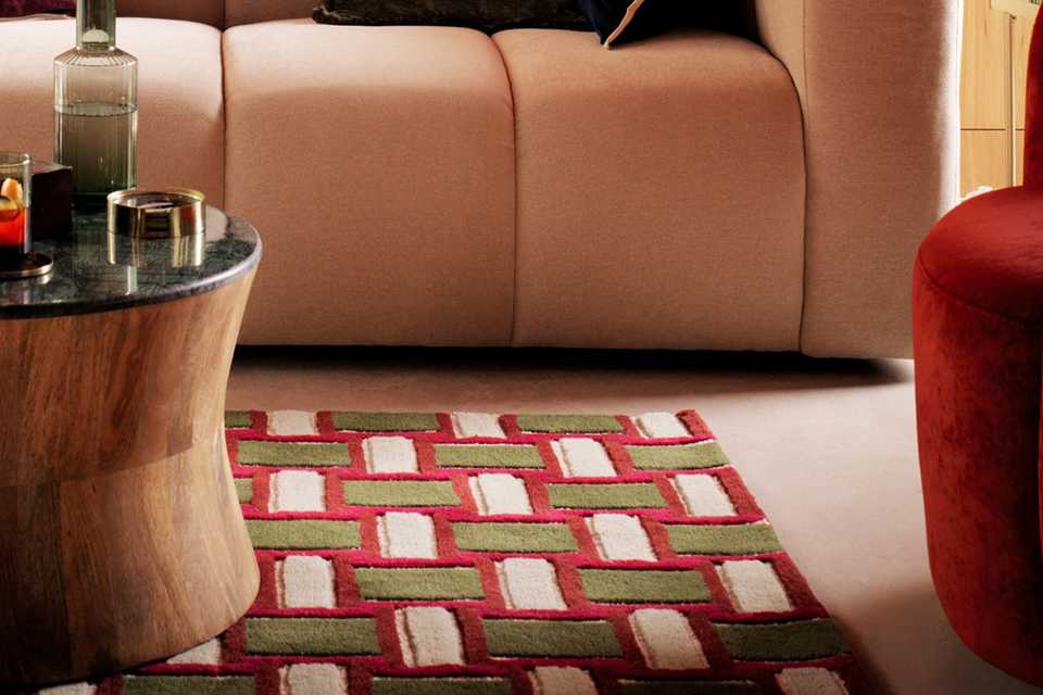 A coffee table, a cosy sofa, a wine red armchair and a Habitat Archive Mid Century Burgundy Wool Rug in a living room.
