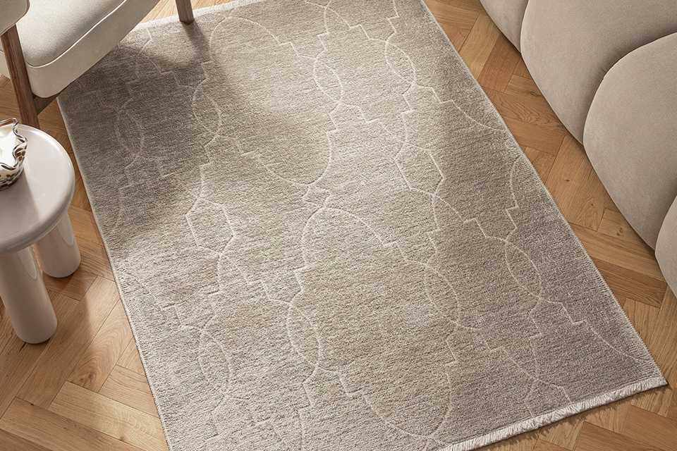 A grey armchair on a Habitat Luxe Chenille Neutral Flatweave Rug.