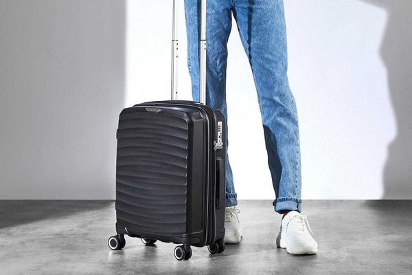 A woman with a Rock Expandable 8 wheel small hard suitcase in black.