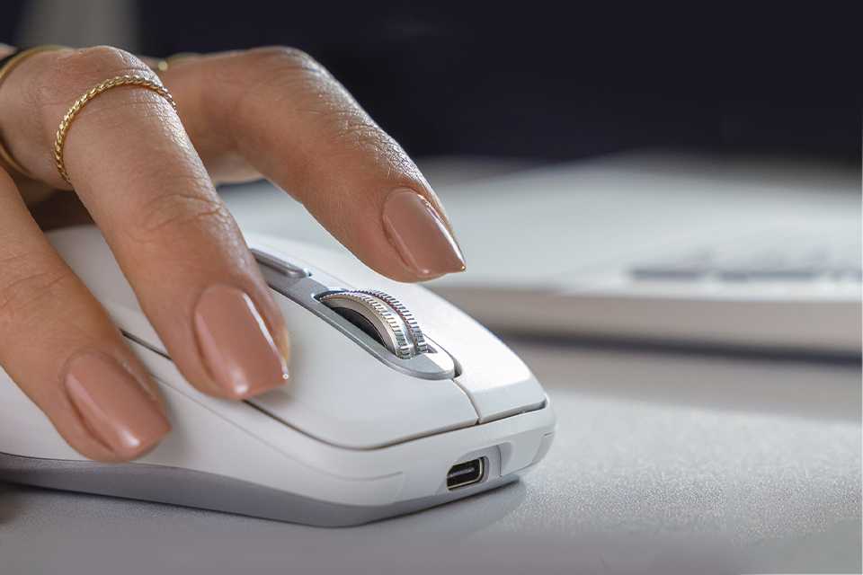 A woman using a Logitech MX Anywhere 3S wireless mouse to scroll on her laptop.