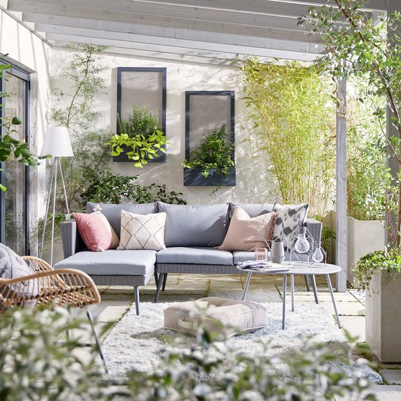 Image of a conservatory with grey corner sofa, grey rug and bamboo chair.