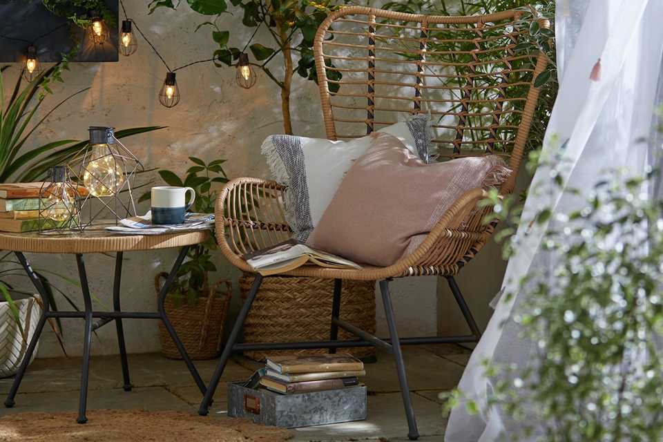 Image of a bamboo chair with cushions surrounded by string lights.