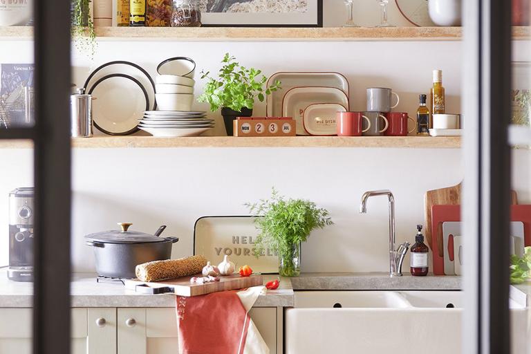 White kitchen with wooden shelving stacked with kitchen accessories.