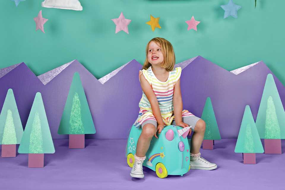 A girl sitting on a blue travel bag.
