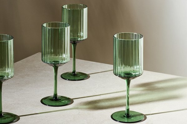 Habitat green wide ribbed set of 4 wine glasses on a table.