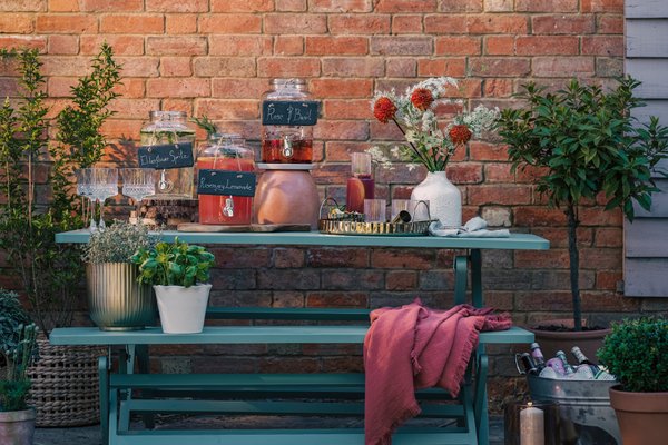 Cocktails at dusk on a green garden bench.