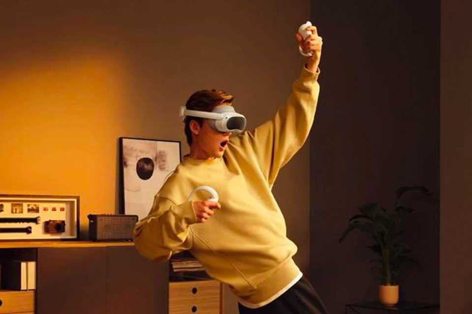A teen boy playing a game on a PICO 4 all-in-one VR headset.